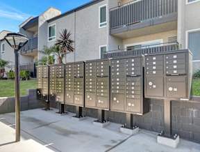A row of mailboxes are lined up on a sidewalk.