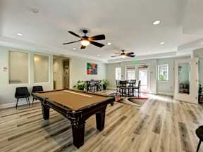 A room with a pool table and chairs.