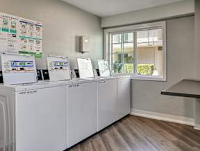 A laundry room with a row of washing machines and a signboard.