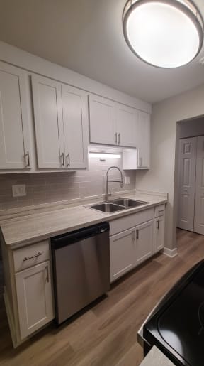 an empty kitchen with white cabinets and a sink