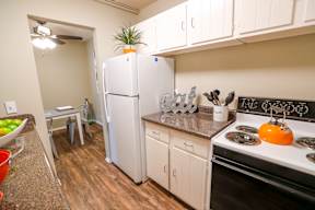 A kitchen with a white refrigerator, black stove, and wooden cabinets.