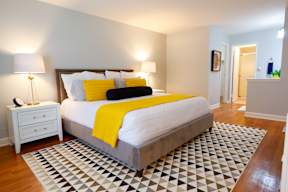 A bedroom with a bed, nightstand, and lamp.