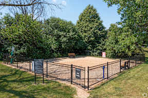 A fenced area with a sign and a tree in the background.