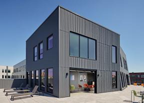 A modern building with a black exterior and large windows.