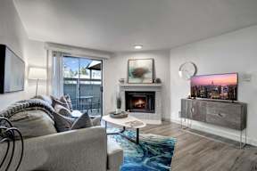 a living room with a fireplace and a sliding glass door to a balcony