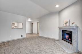 a living room with a fireplace and a kitchen in the background