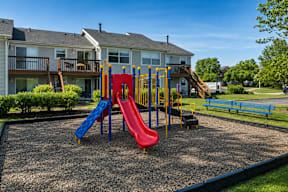 A playground with a red, yellow and blue slide.