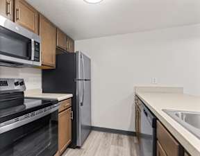 A kitchen with black appliances and wooden cabinets.