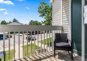 A balcony with a black chair and a white railing.