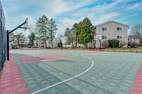 A basketball court with a green and red surface and a basketball hoop.