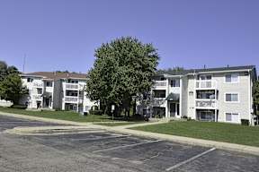 Apartment complex with a parking lot in front.