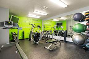 A gym with a green wall that says "challenge inspire succeed".