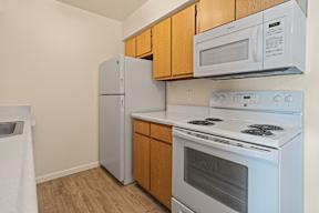 A white stove and microwave are installed above a white refrigerator in a kitchen.