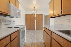 A kitchen with wooden cabinets and a white counter top.