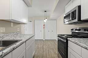 A kitchen with white cabinets and a black stove top oven.