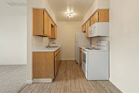 A kitchen with white appliances and wooden cabinets.