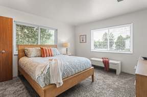 A bedroom with a bed, a bench, and a window.