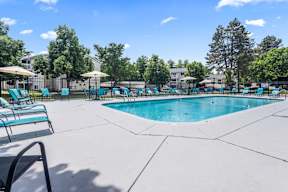 A large swimming pool surrounded by lounge chairs and umbrellas.