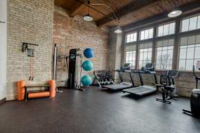 black treadmill three blue yoga balls foam rollers brick room wide windows