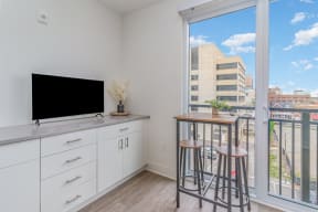 a living room with a balcony and a flatscreen tv and two bar stools  at City View Apartments, Lansing, Michigan