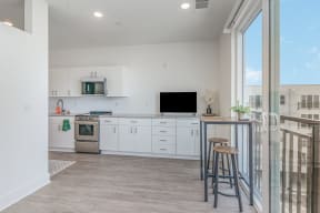 a kitchen with white cabinets and a bar with two stools  at City View Apartments, Lansing, 48933