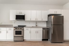 a kitchen with white cabinets and stainless steel appliances and a refrigerator  at City View Apartments, Lansing, MI