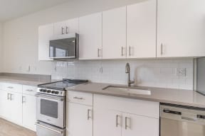 a kitchen with white cabinets and appliances and a sink  at City View Apartments, Lansing, Michigan