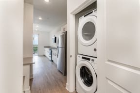 a washer and dryer in a laundry room with a kitchen  at City View Apartments, Lansing, MI