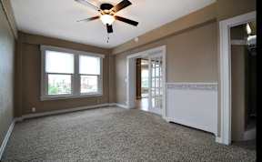 Carpeted bedroom with ceiling fan and double doors with glass panes.