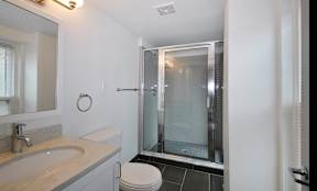 Updated modern bathroom with slate tile flooring and standing shower.