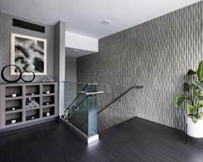 A modern hallway with a glass railing and a grey wallpapered wall.