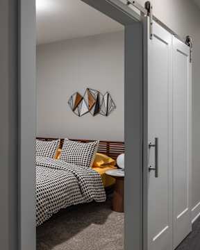 A bedroom with a bed, nightstand, and a wall hanging.