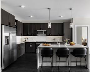 A modern kitchen with a large island and black bar stools.
