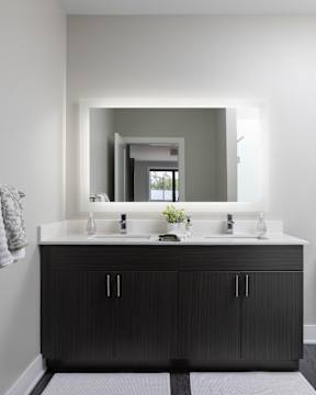A bathroom with a double sink vanity and a large mirror above it.