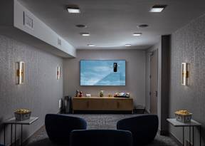 A modern living room with a large screen and comfortable seating.