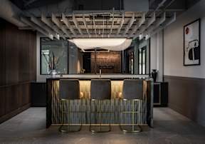 A bar with two stools and a gold and grey backrest.