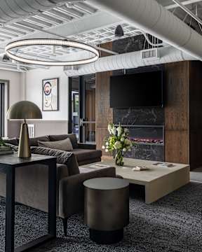 A modern living room with a grey carpet and a fireplace.