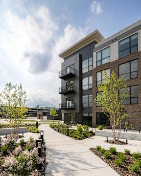 A modern building with a balcony and a walkway in front.