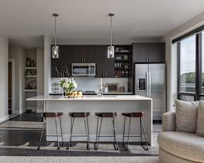 A modern kitchen with a bar stool and a refrigerator.