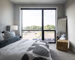 A bedroom with a large bed and a view of the street outside.