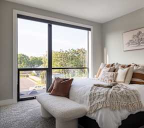 A bedroom with a large bed and a view of a parking lot through a sliding glass door.