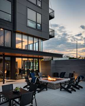 A modern patio with a fire pit and seating area.