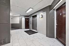 A hallway with marble tiles and doors on both sides.