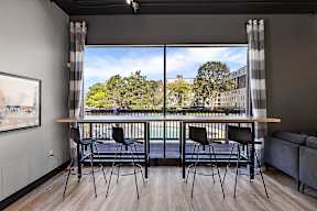 A room with a table and chairs in front of a window with a view of a cityscape.