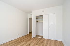 A white door is open to a room with a wooden floor.