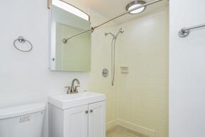 A white bathroom with a sink, mirror, and shower.