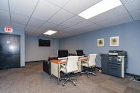 A room with a desk, chairs, and computers.