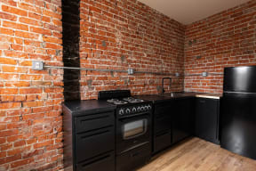 a kitchen with black cabinets and a brick wall
