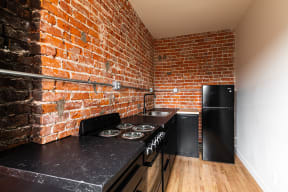 a kitchen with a black counter top and a brick wall