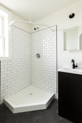 a small bathroom with white subway tile and a black and white tile floor